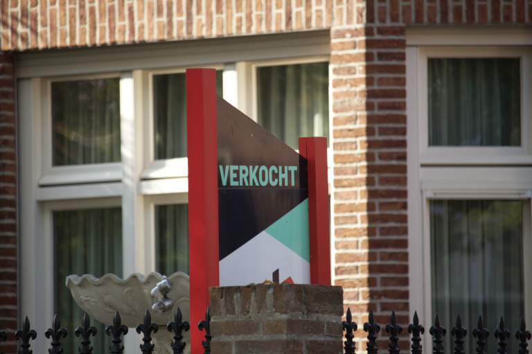 Verkoopbord van een woning waarop verkocht staat